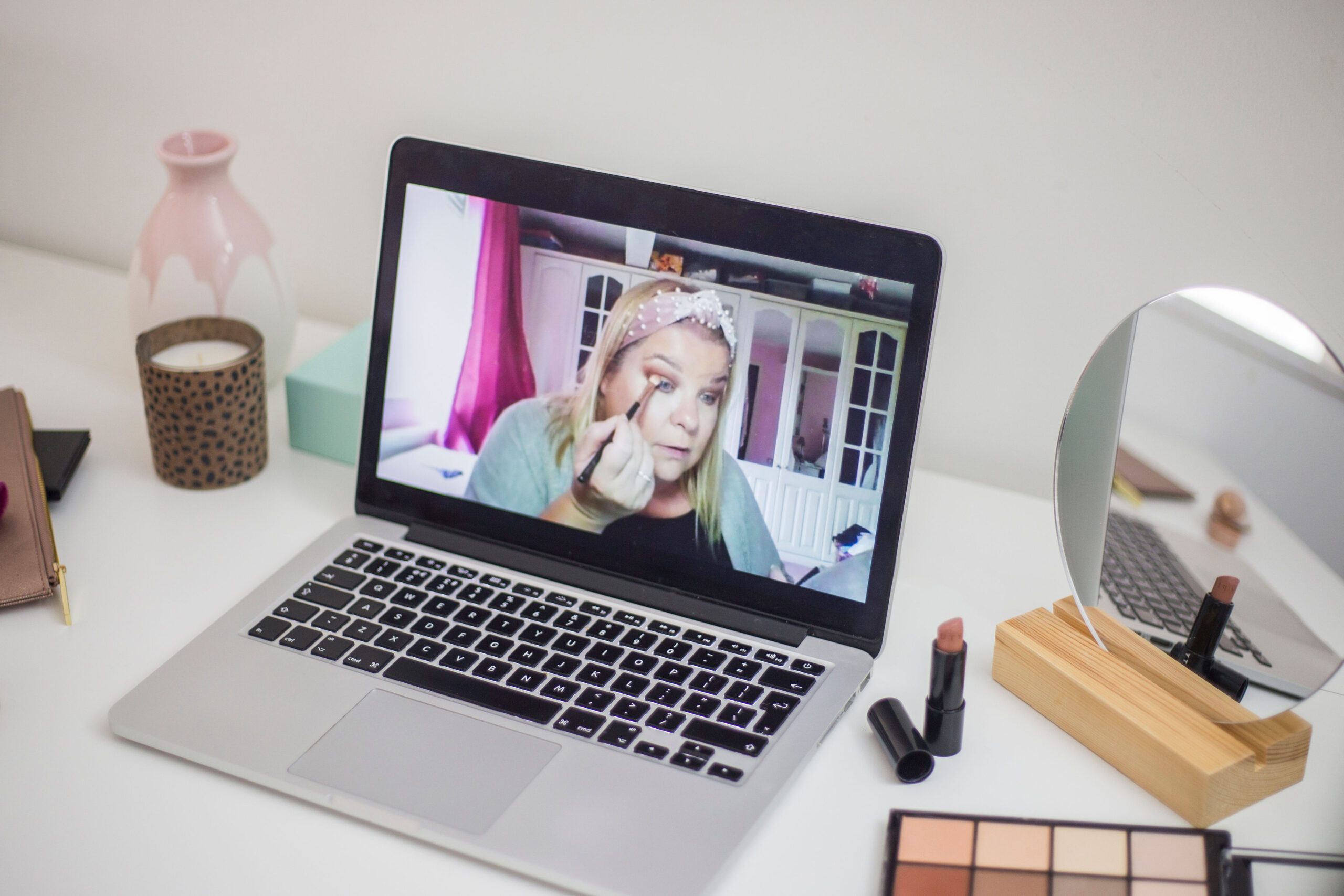 online makeup lesson on zoom on a laptop with makeup brushes and makeup