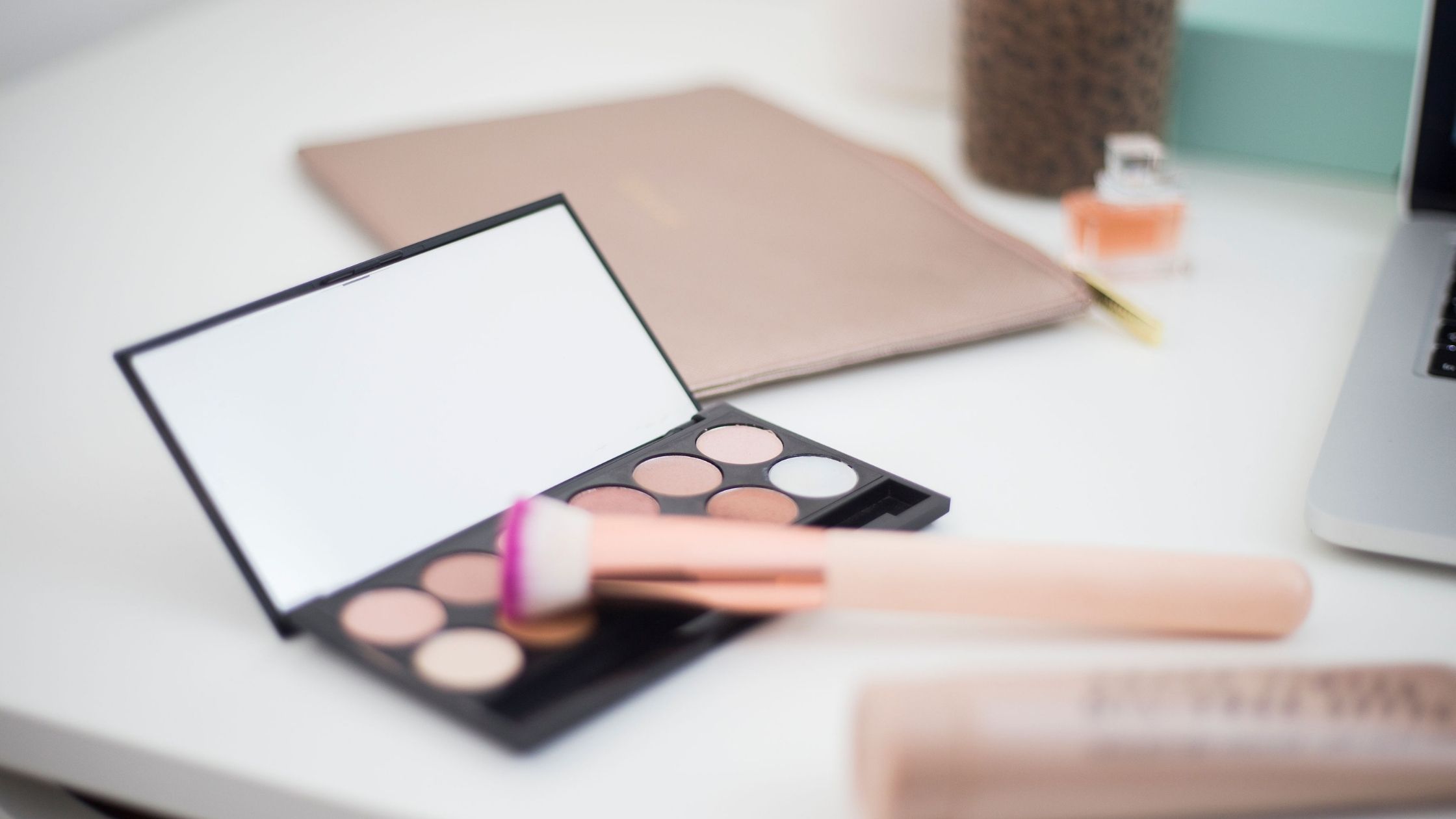 eye shadow palette and makeup brush on a white table
