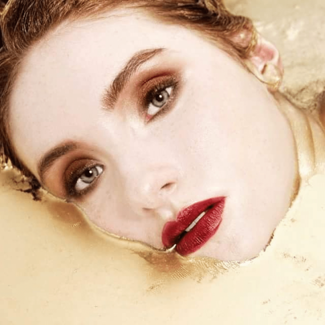 model in gold bath with red lip editorial makeup by Vicky King